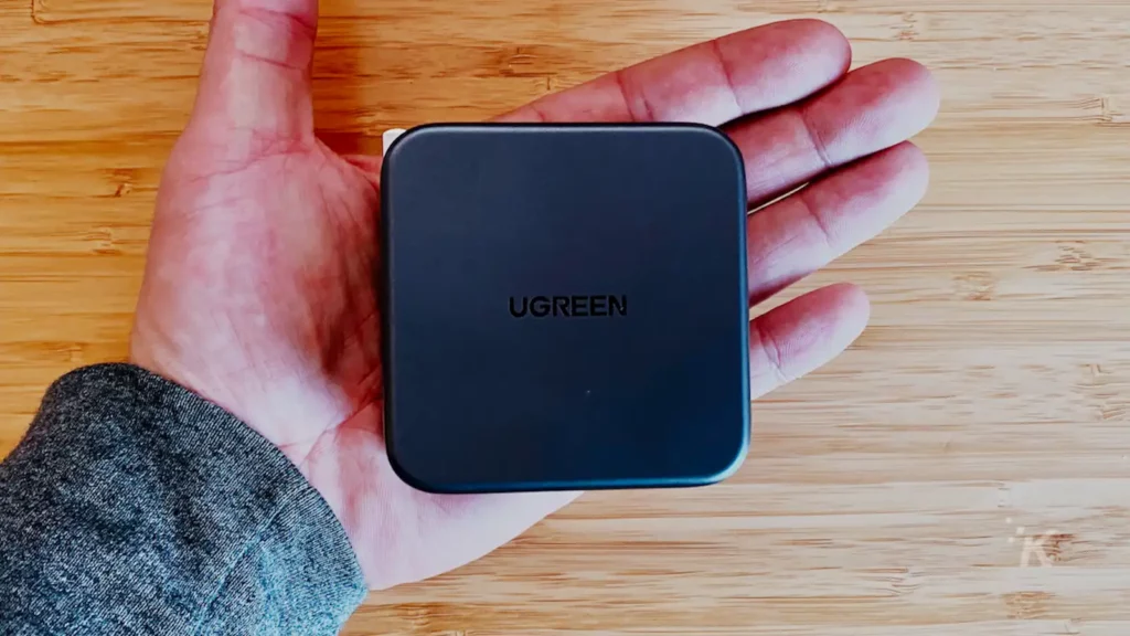 让你在 kevin raposo 的手中拿着绿色的 USB c 壁式充电器在一张木桌上