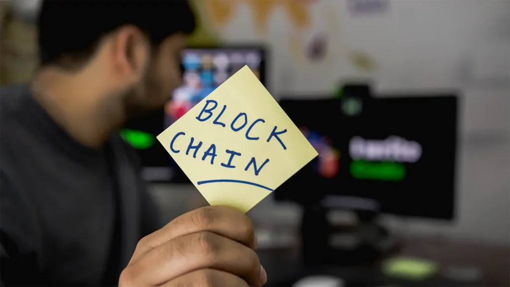 hombre sosteniendo un post con la palabra Blockchain escrita