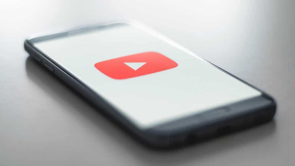 坐在桌子上的手机上的 youtube 标志