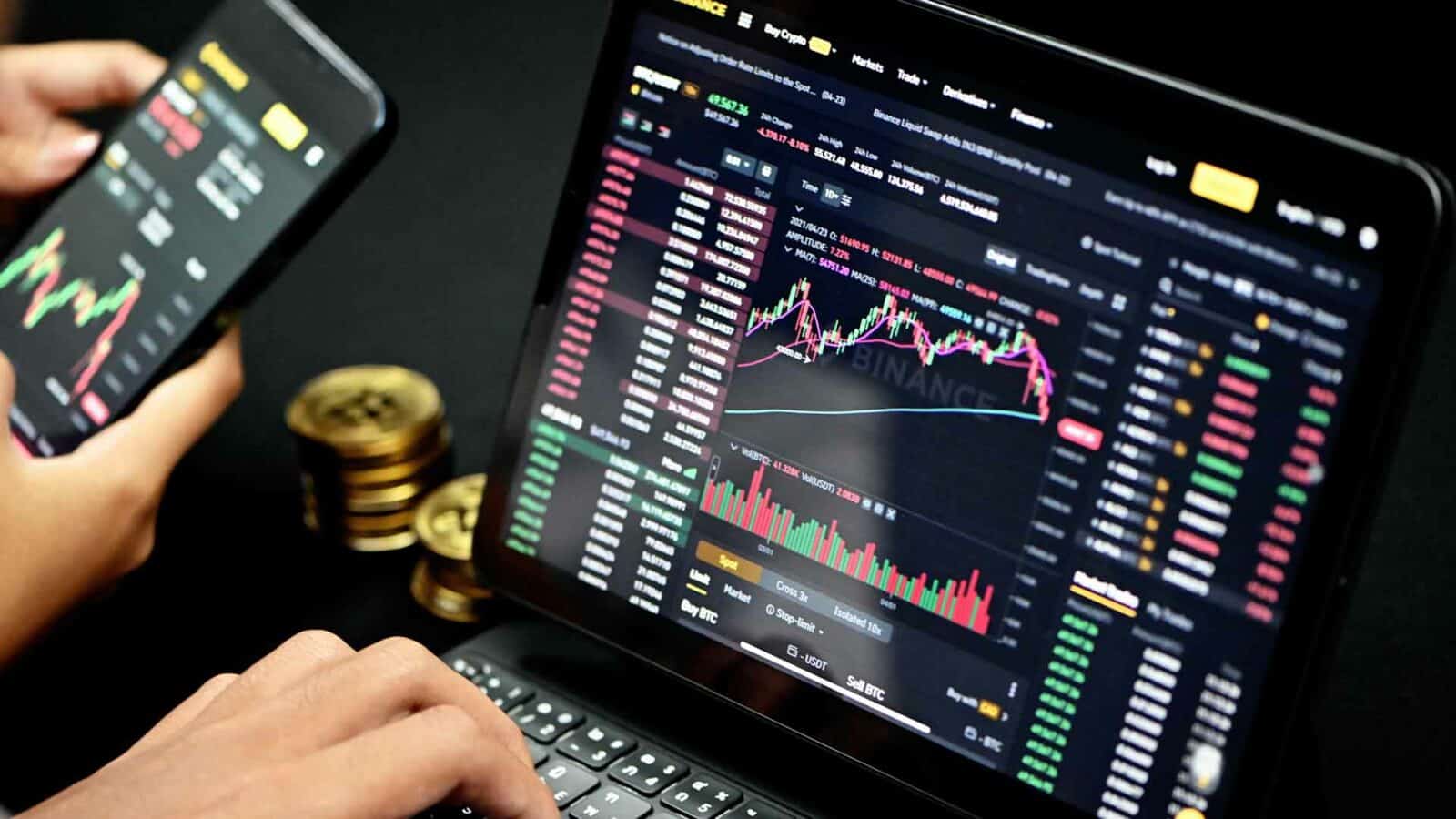Kryptowährung: Eine Person verwendet einen Laptop, um einen Screenshot von Markets Trade, Binance Liquid Swap und anderen elektronischen Geräten auf dem Computerbildschirm anzuzeigen.