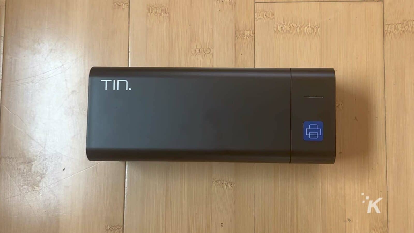 Un appareil rectangulaire noir repose sur une surface en bois.