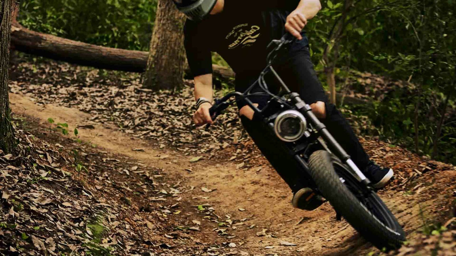 Osoba jedzie na ebike na szlaku w lesie.