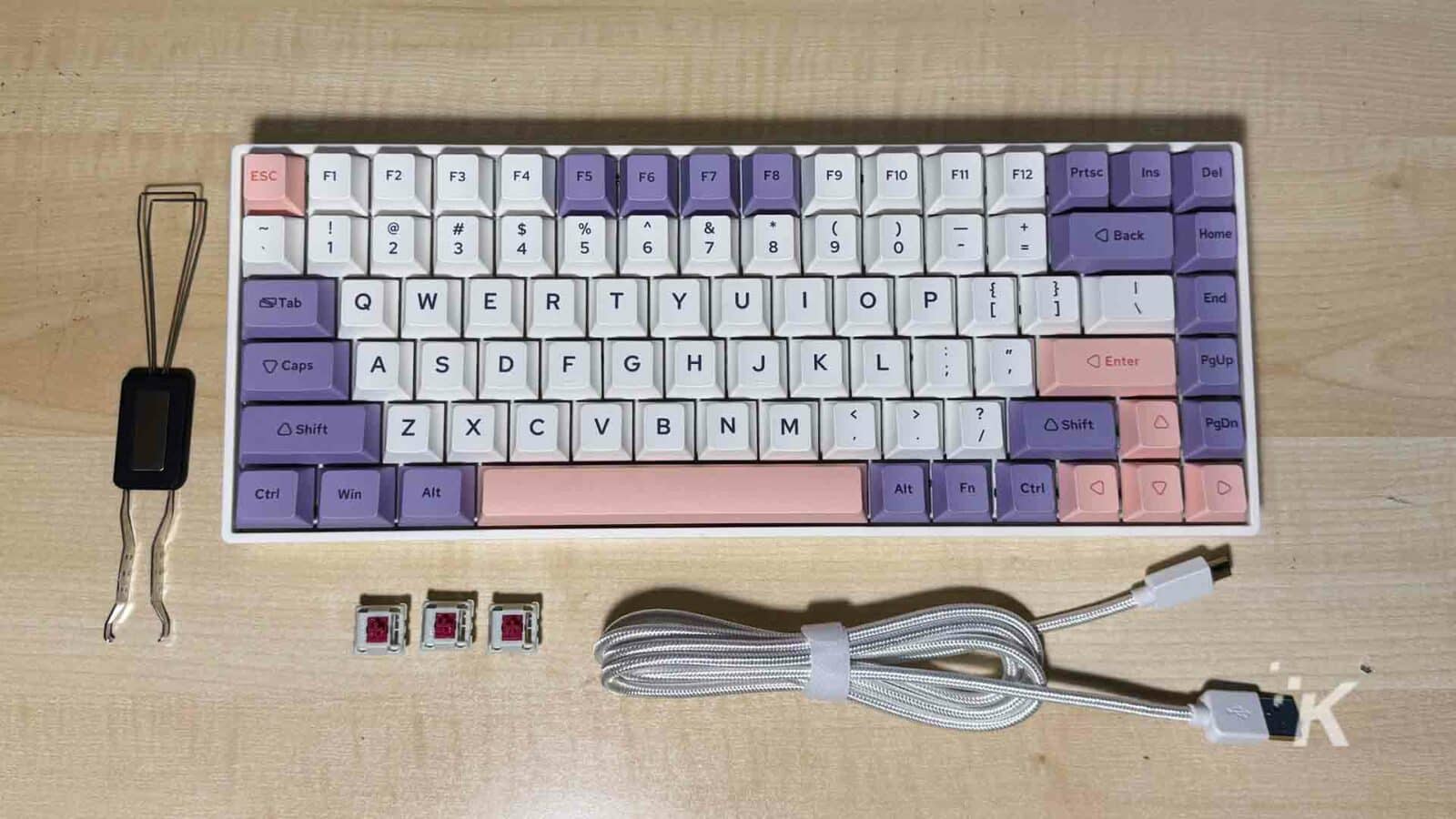 Un teclado con varios dispositivos de entrada, componentes informáticos y material de oficina en una superficie interior. Bp84 plus con accesorios
