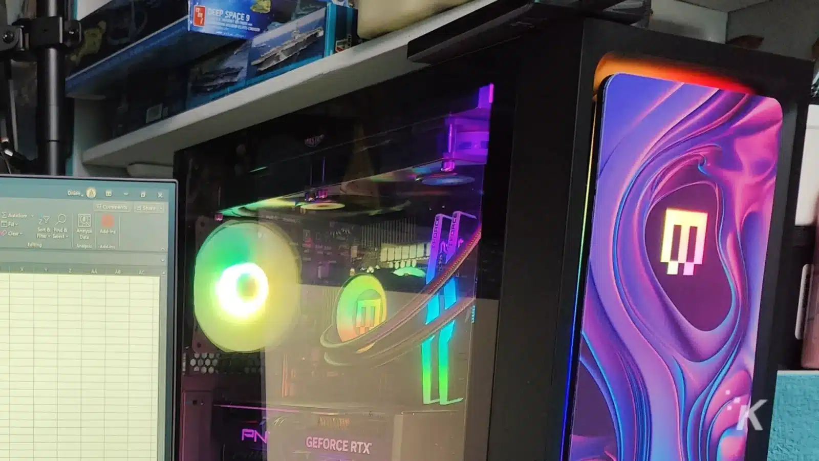 evaluando el excelente maingear mg-1 platinum A desktop pc with rgb lighting visible through a clear side panel, featuring a geforce rtx graphics card, beside a monitor with colorful wallpaper.