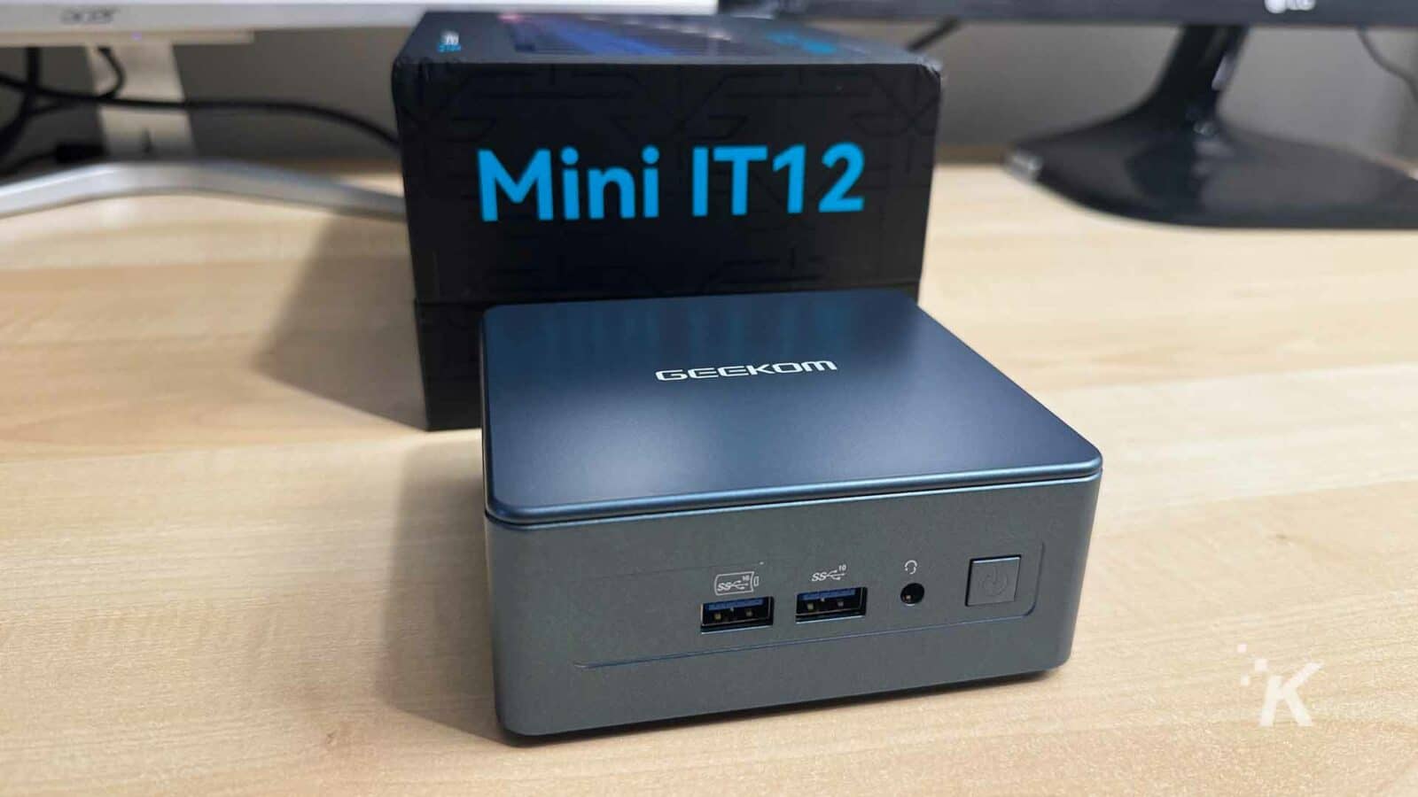Geekom mini it12 pc nella scatola su una scrivania in legno