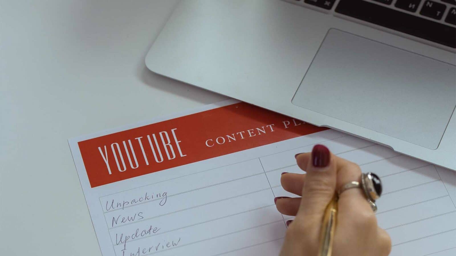 Dizüstü bilgisayarın yanında youtube için içerik yazan kişi