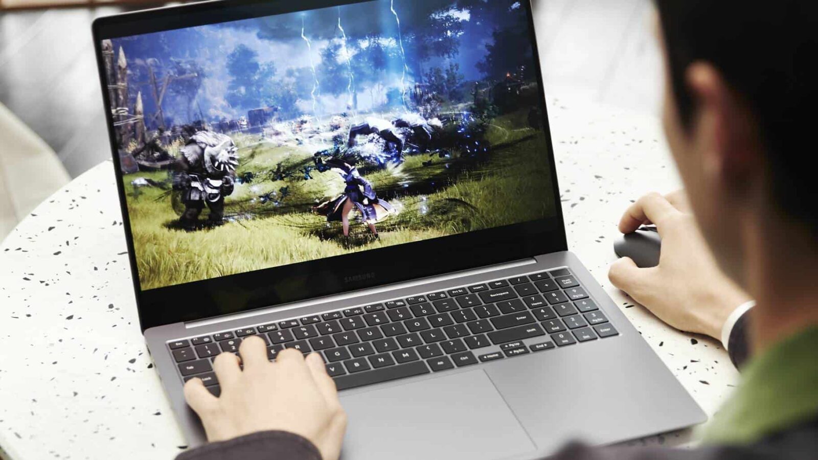 Personne jouant à un jeu vidéo fantastique sur un ordinateur portable, montrant à l'écran un personnage brandissant la magie contre des monstres.