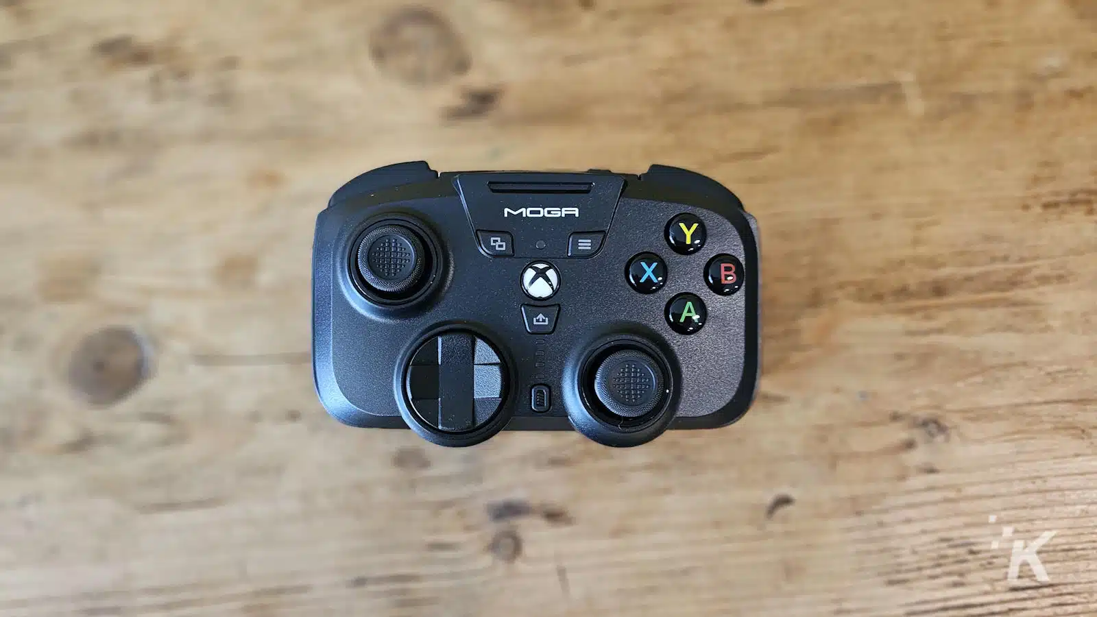 Controler de joc MOGA Xbox pe suprafață de lemn.