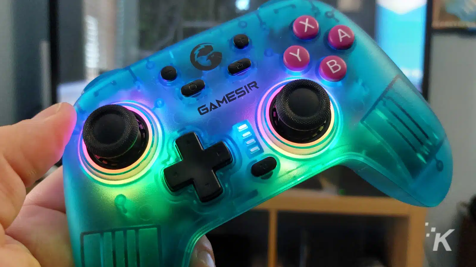 Mână ținând controler de joc GameSir iluminat albastru.