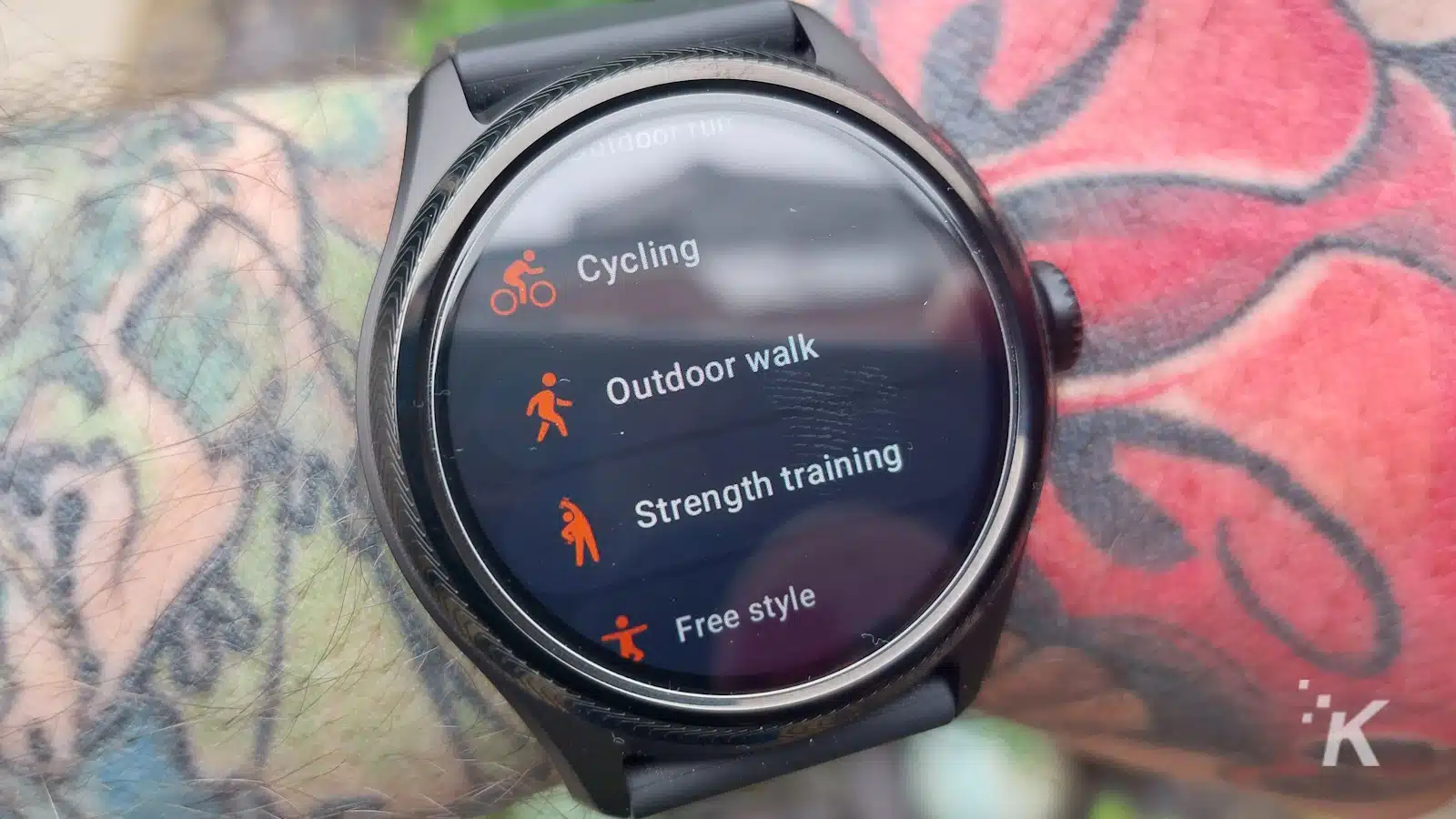 タトゥーの入った手首にフィットネス追跡オプションを備えたスマートウォッチ。