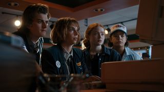 Steve, Dustin, Max e Robin parecendo surpresos com uma tela de computador em Stranger Things 4