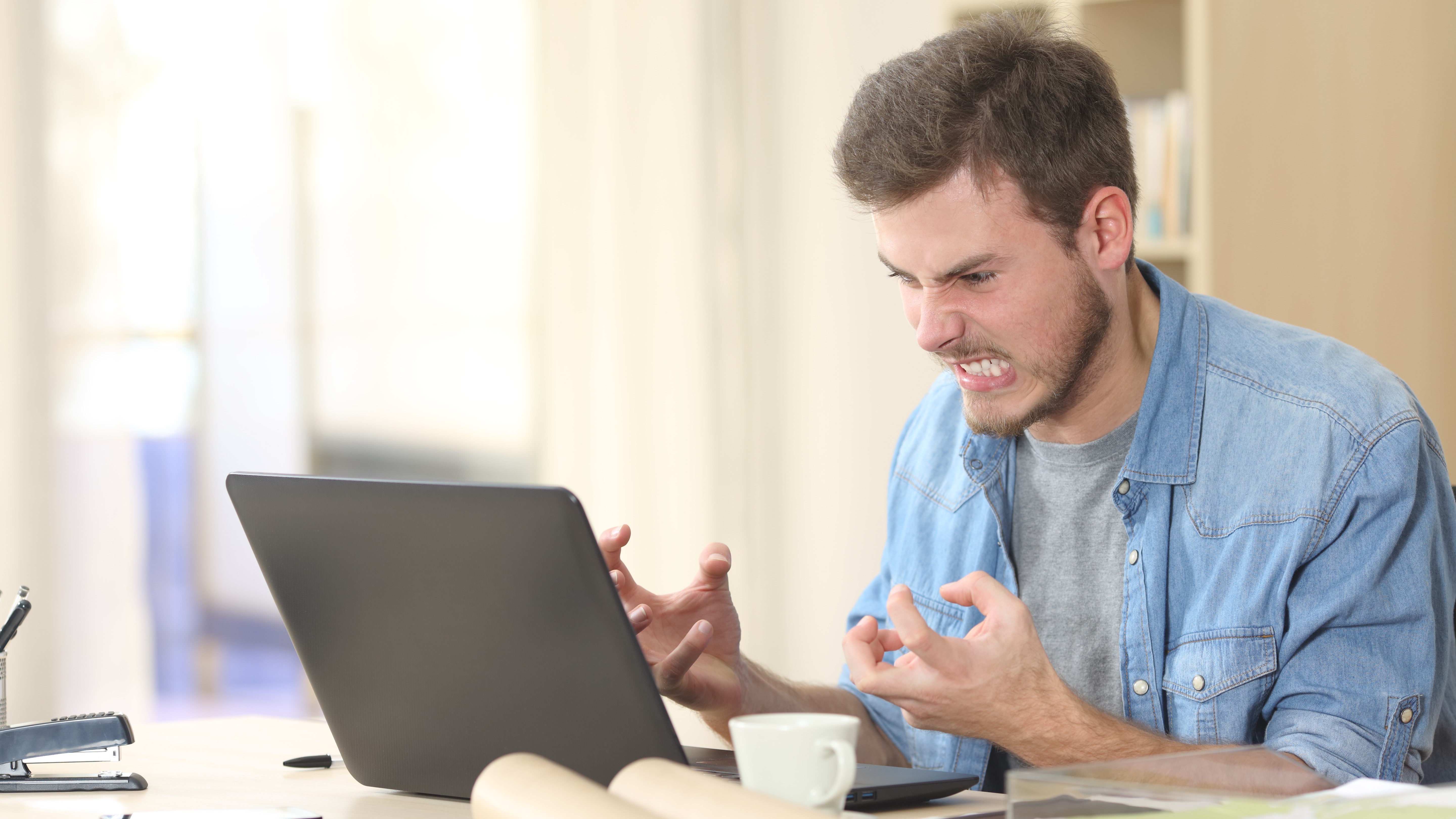 Un uomo si arrabbia con il suo laptop.