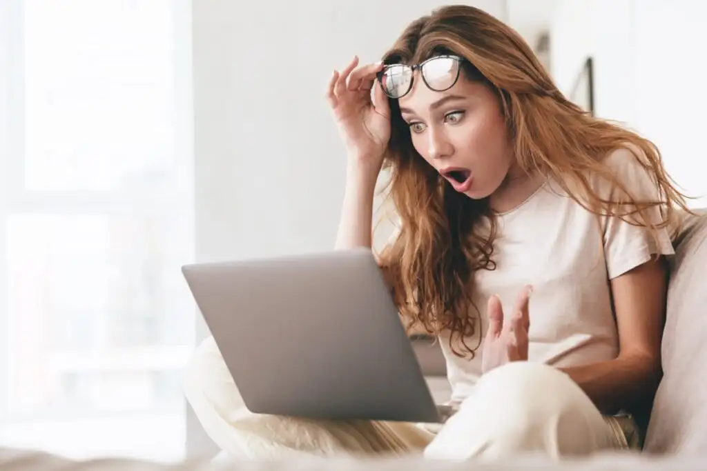 femeie care arată șocată de ceea ce vede pe computerul ei